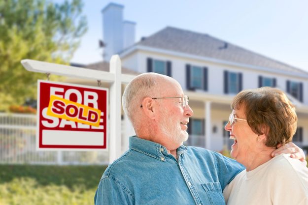 senior couple in front of sold real estate sign house senior couple in front of sold real estate sign house
