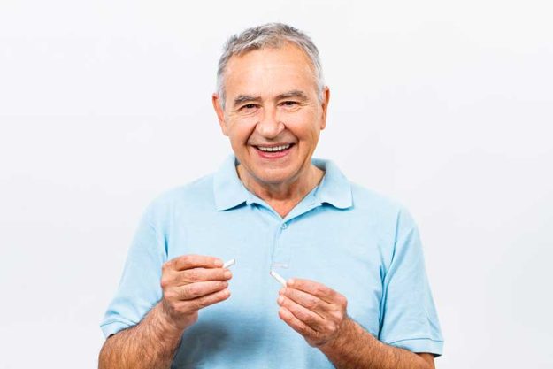 senior man breaking cigarette senior man breaking cigarette