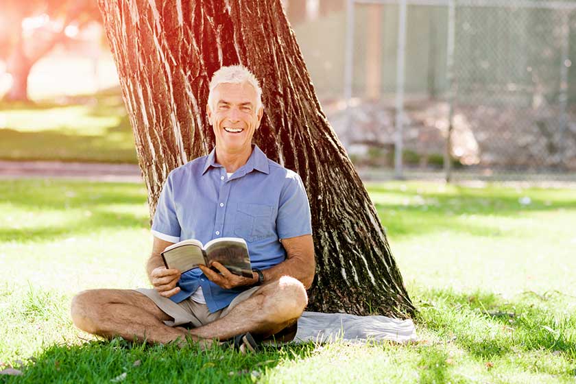 senior man sittingin park while reading book