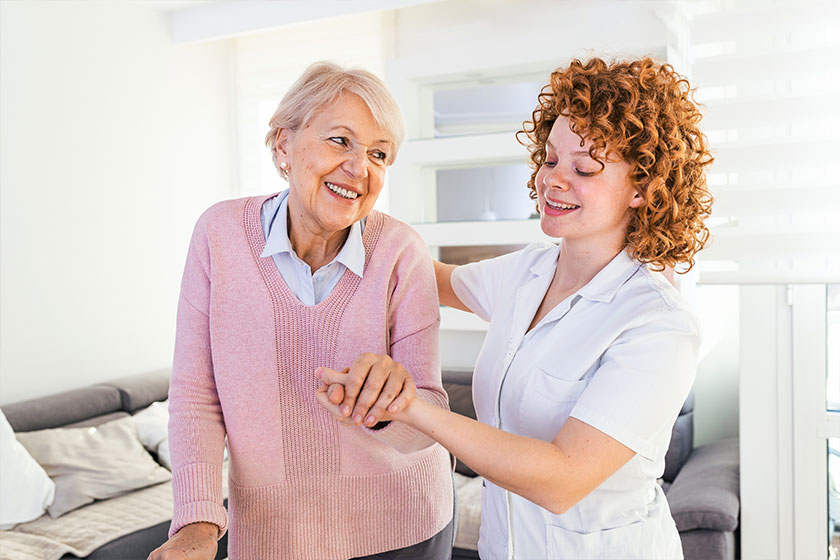 smiling nurse helping senior lady to walksmiling