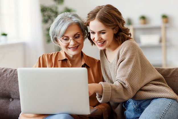 young woman with mother using laptop