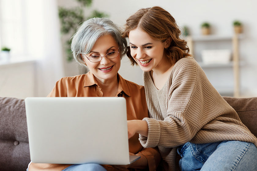 young woman with mother using laptop