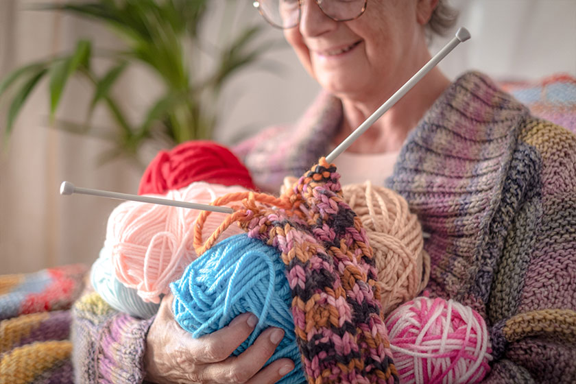 caucasian senior woman at home holding in her hands wool balls
