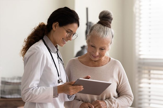 happy female doctor and senior patient look at tablet screen happy female doctor and senior patient look at tablet screen