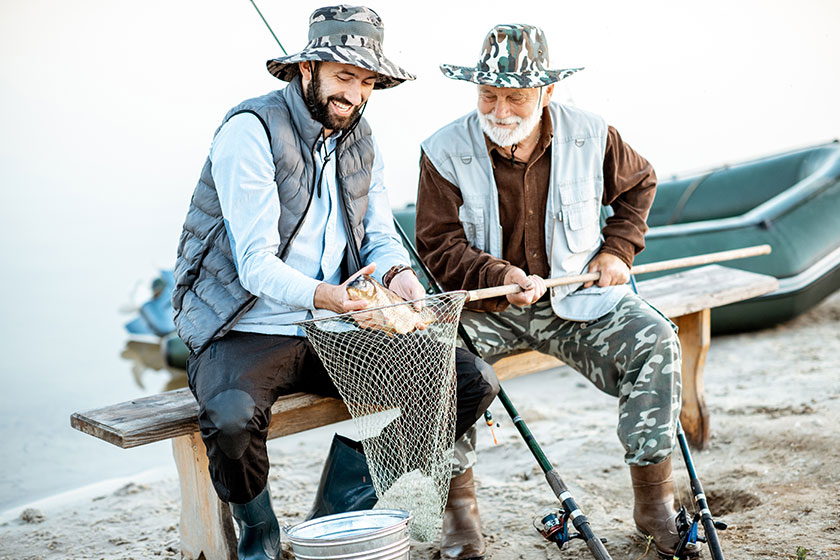 happy grandfather with son holding freshly caught fish