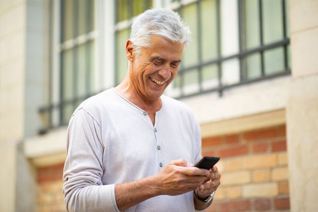 mature man squinting using cell phone looking at screen