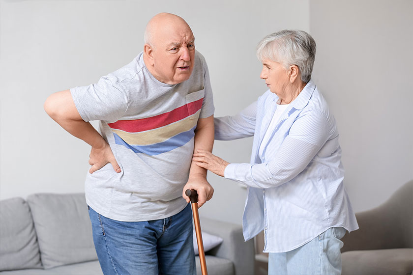 senior man with walking stick suffering from back pain