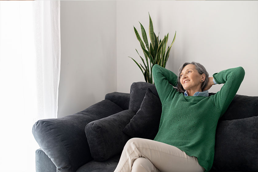 view tranquil calm middle aged hoary woman crossed hands behind head relaxing on cozy sofa