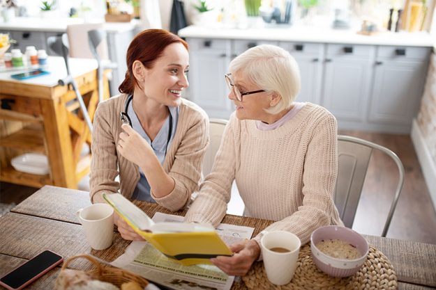 woman and caregiver drinking tea and reading