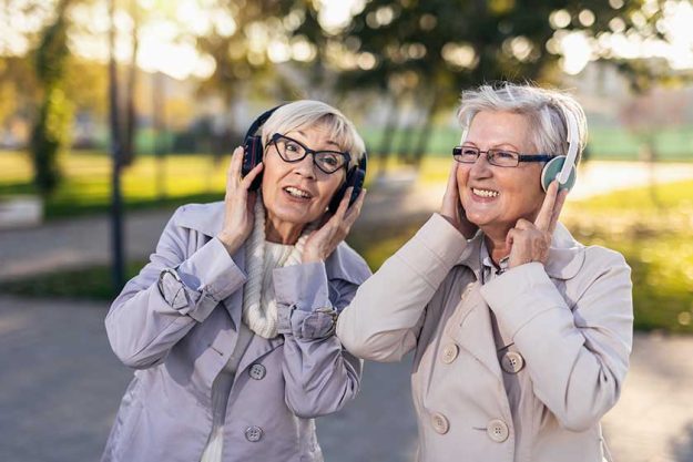 senior female friends listening to music in nature