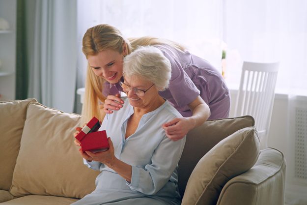 smiling daughter giving a present to a elderly mother