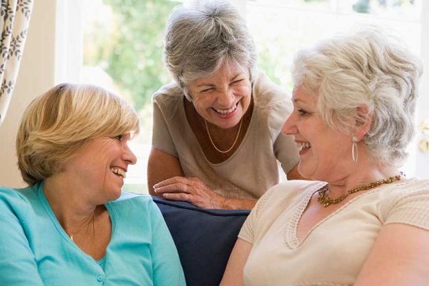three women in living room talking and smiling