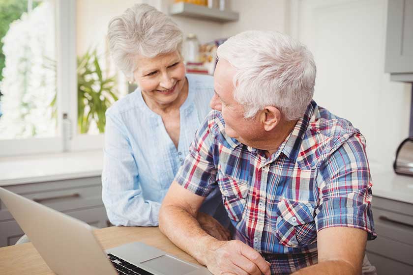 senior couple talking while using laptop