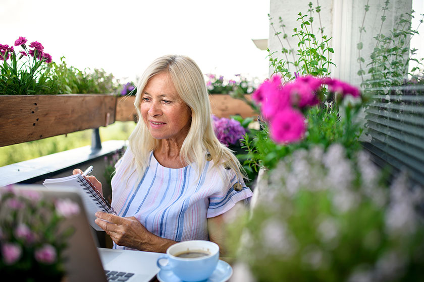 active senior woman with laptop working on balcony home office