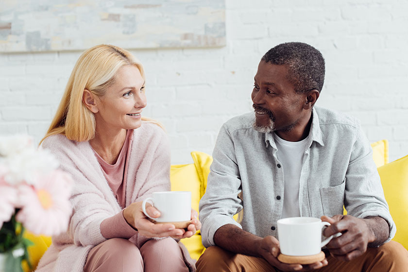 smiling mature woman sitting sofa african american man drinking coffee smiling mature woman sitting sofa african american man drinking coffee
