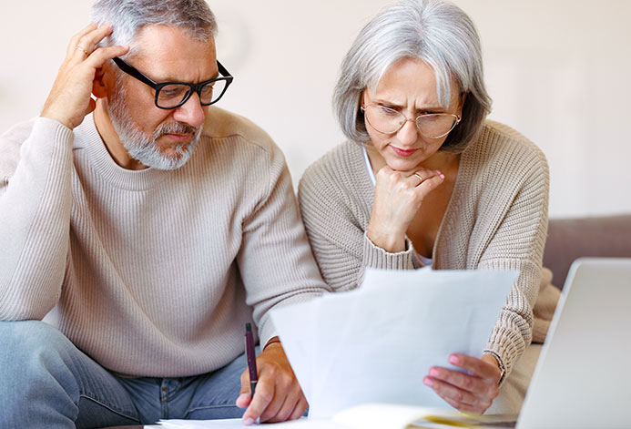 worried senior family reading financial documents or notification letter with bad news from bank