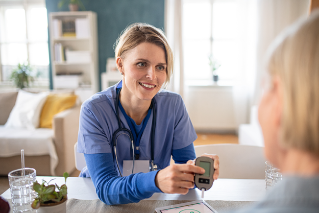 caregiver or healthcare worker with senior woman patient measuring blood glucose