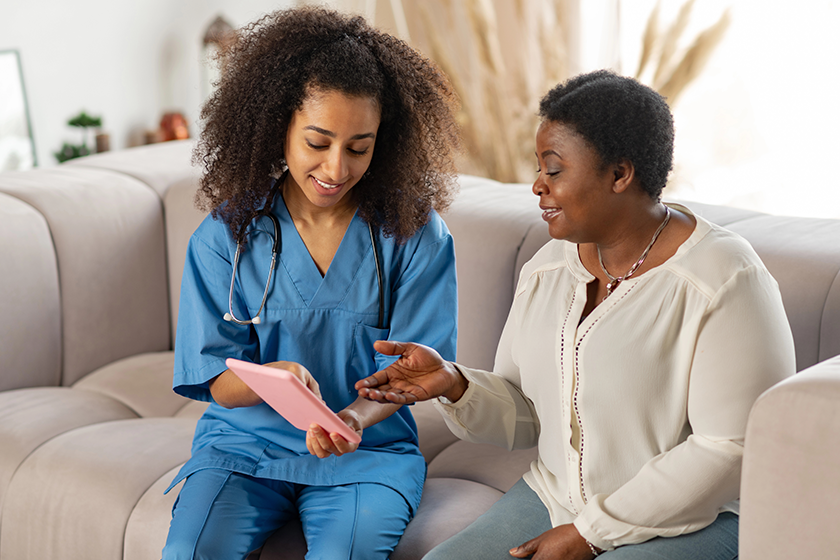 elderly dark skinned lady feeling joyful while talking to nurse elderly dark skinned lady feeling joyful while talking to nurse