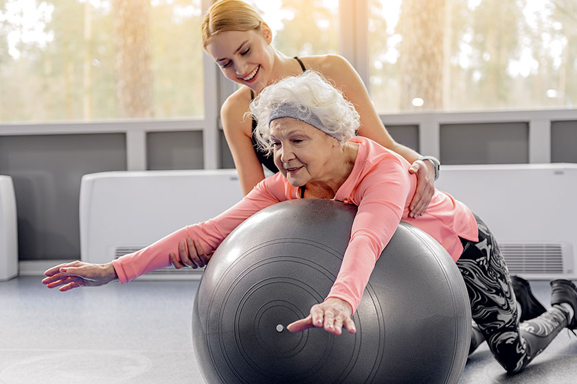 smiling retiree leaning on fitball smiling retiree leaning on fitball