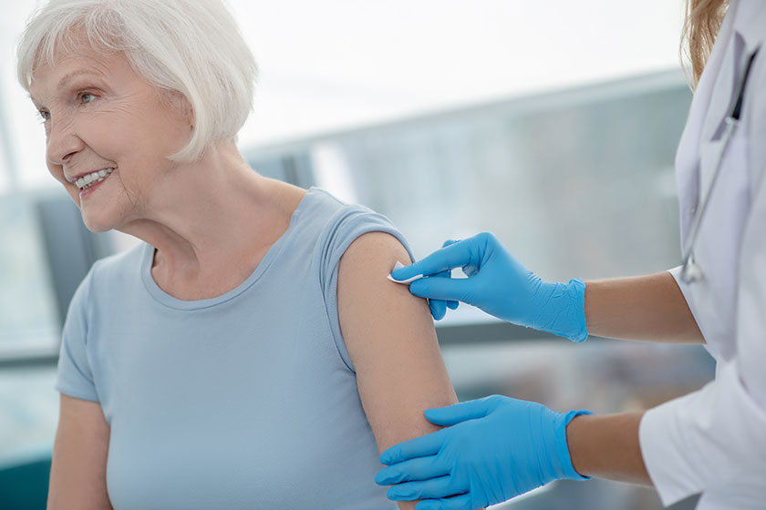 nurse making an injection to an elderly smiling woman nurse making an injection to an elderly smiling woman