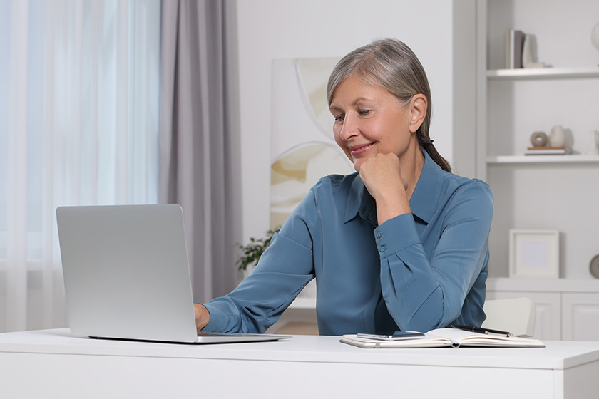 beautiful senior woman using laptop white table indoors