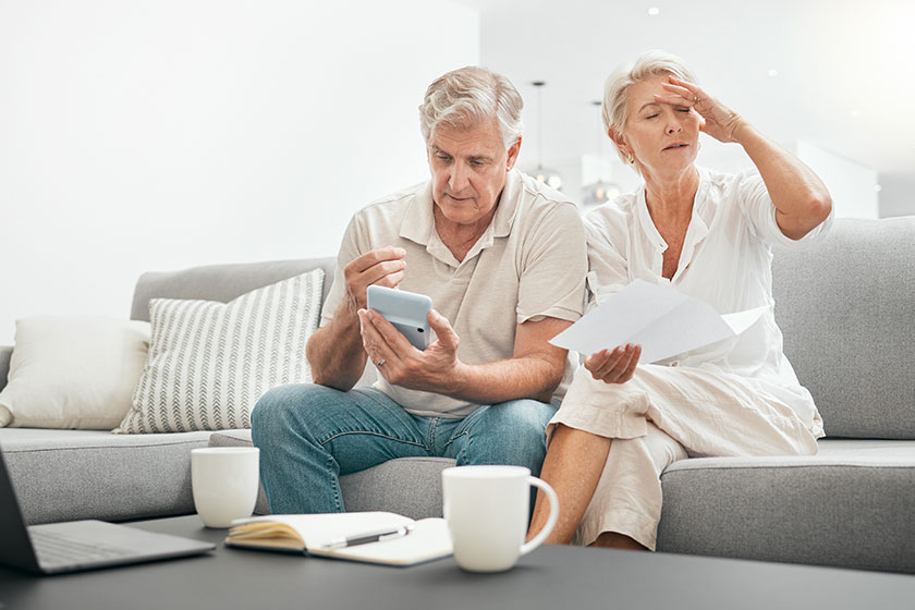 frustrated senior couple documents debt living room sofa financial crisis