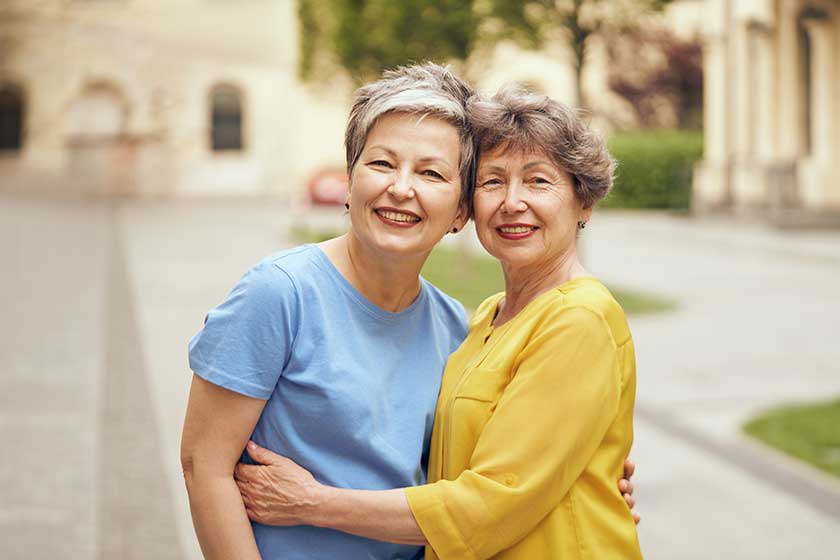 happy middle age women hug look camera city street female