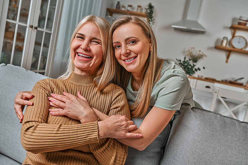 loving tender mother beautiful blond daughter hugs her mom smiling