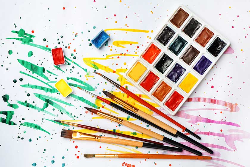 plastic palette with colorful paints and brushes on light background top view