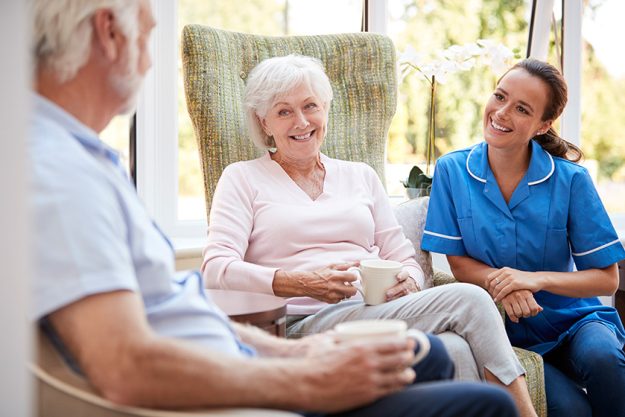 senior couple sitting chair talking nurse retirement home senior couple sitting chair talking nurse retirement home