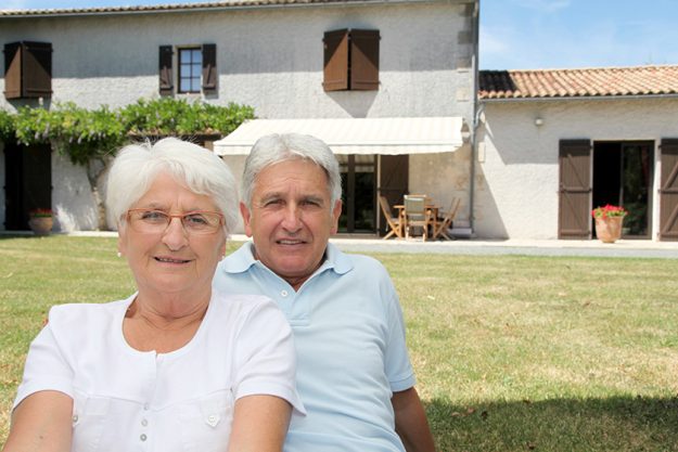 senior couple sitting in front of a house senior couple sitting in front of a house