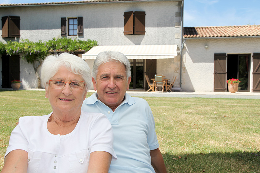 senior couple sitting in front of a house
