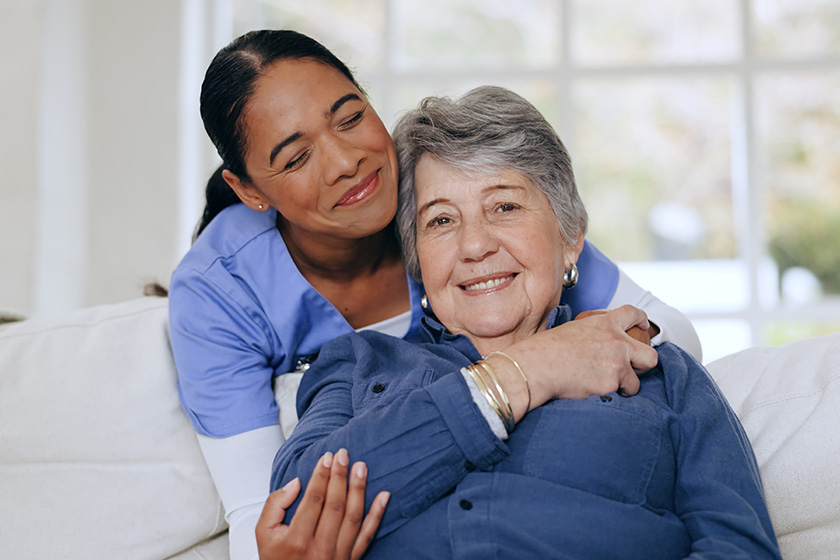 senior woman nurse hug sofa retirement home caregiver support smiling senior woman nurse hug sofa retirement home caregiver support smiling