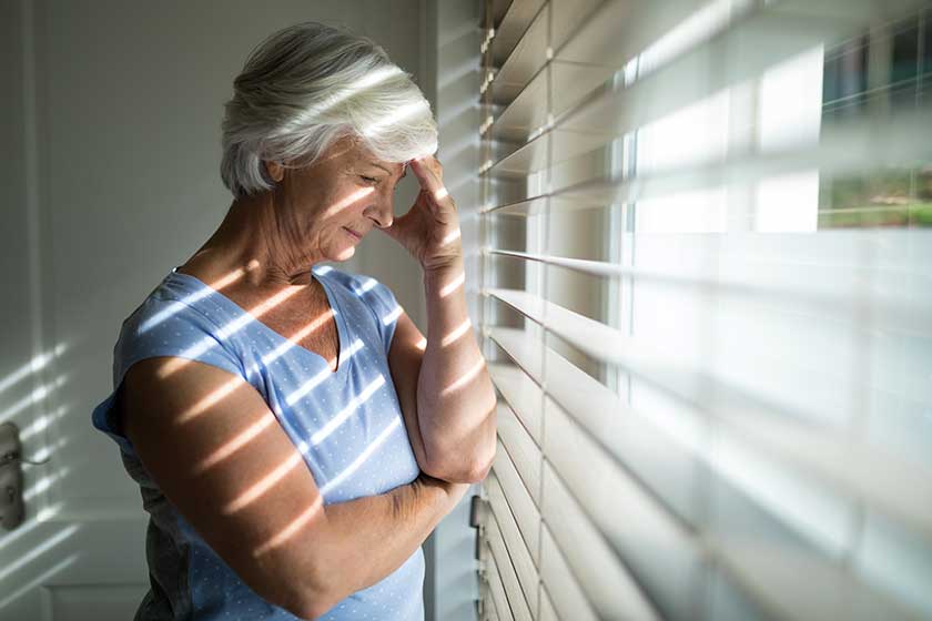 tense senior woman near window tense senior woman near window