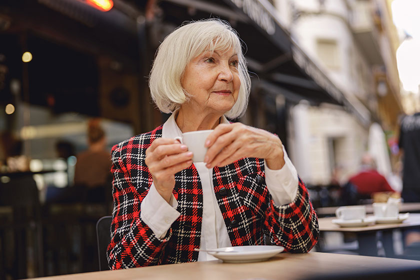 thoughtful senior woman wearing fashionable plaid jacket looking side while