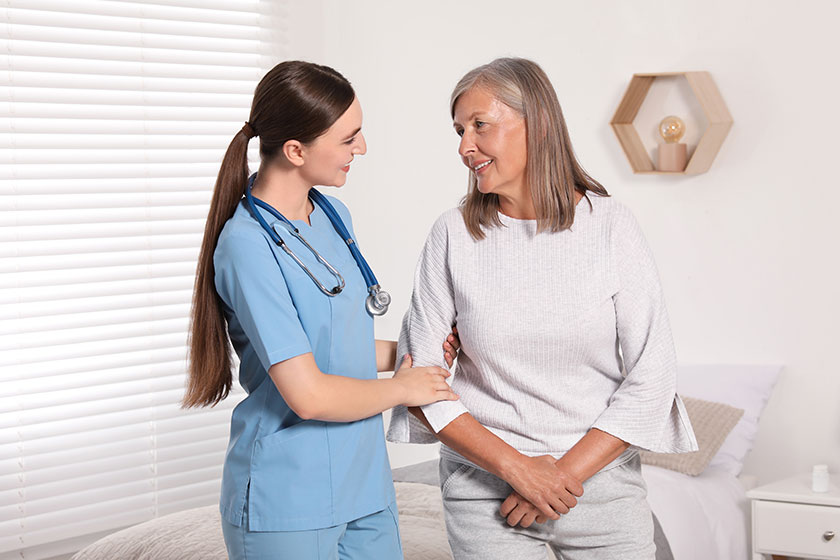 young healthcare worker assisting senior woman indoors young healthcare worker assisting senior woman indoors