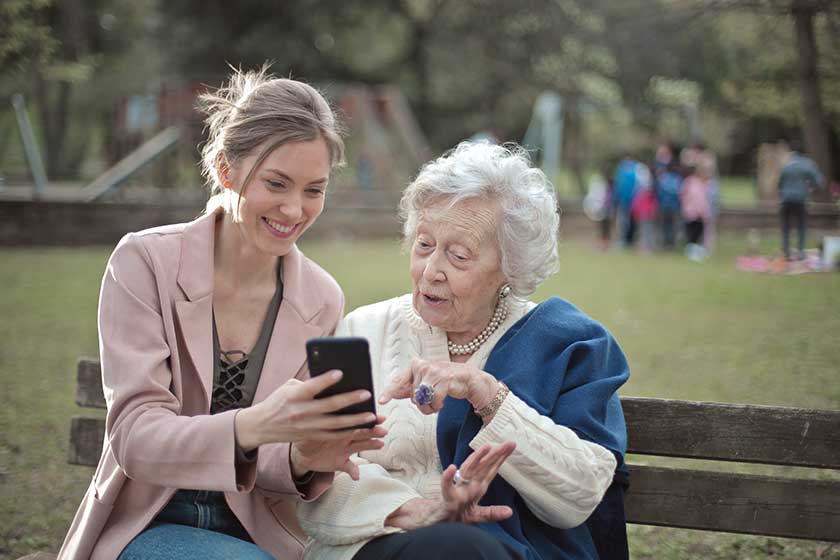young woman teaches old woman use smartphone