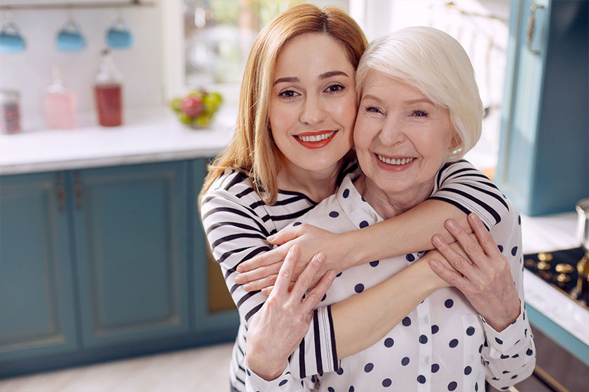 Happy woman hugging her elder mother in kitchen