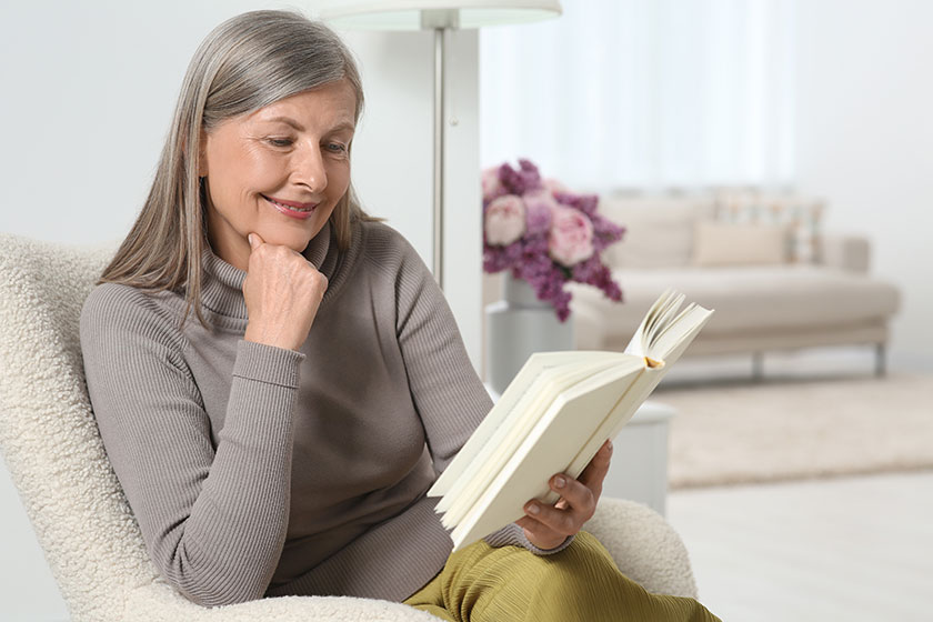 beautiful senior woman reading book armchair home