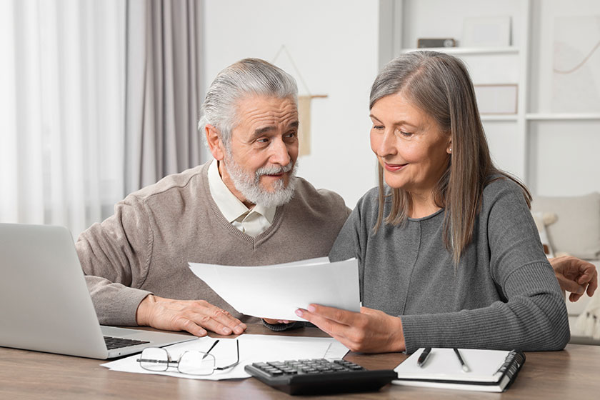 elderly couple papers laptop discussing pension plan wooden table room elderly couple papers laptop discussing pension plan wooden table room