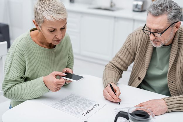 elderly woman taking photo contract husband document coffee kitchen