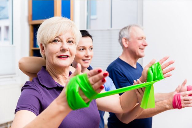 physio showing senior couple how to use rubber band as expander