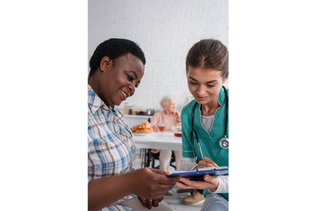 smiling nurse african american patient looking clipboard nursing home smiling nurse african american patient looking clipboard nursing home