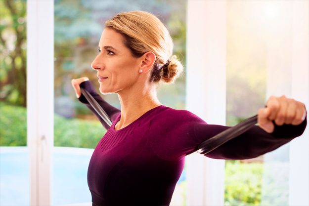 Middle aged woman using resistance band