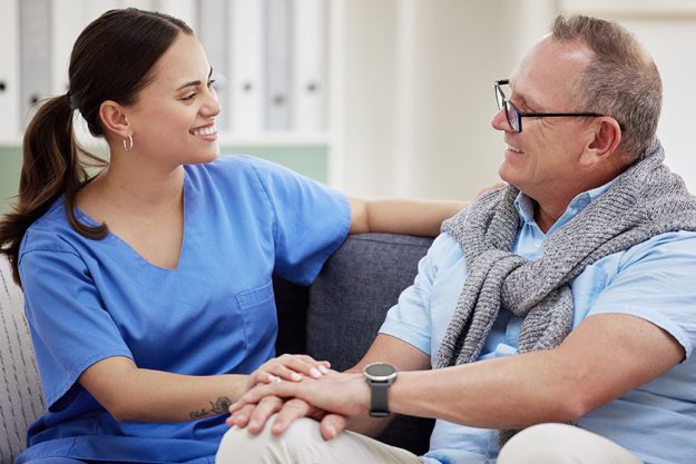 attractive young nurse bonding her senior patient clinic