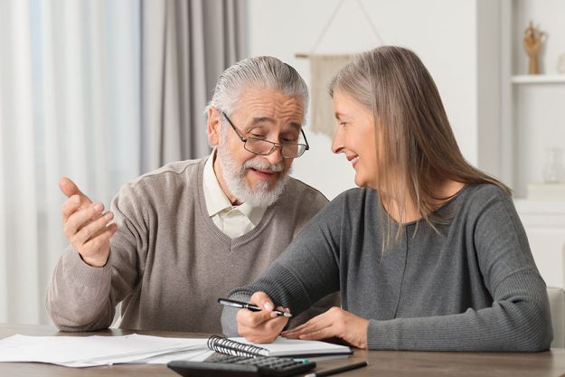 elderly couple papers discussing pension plan wooden table indoors