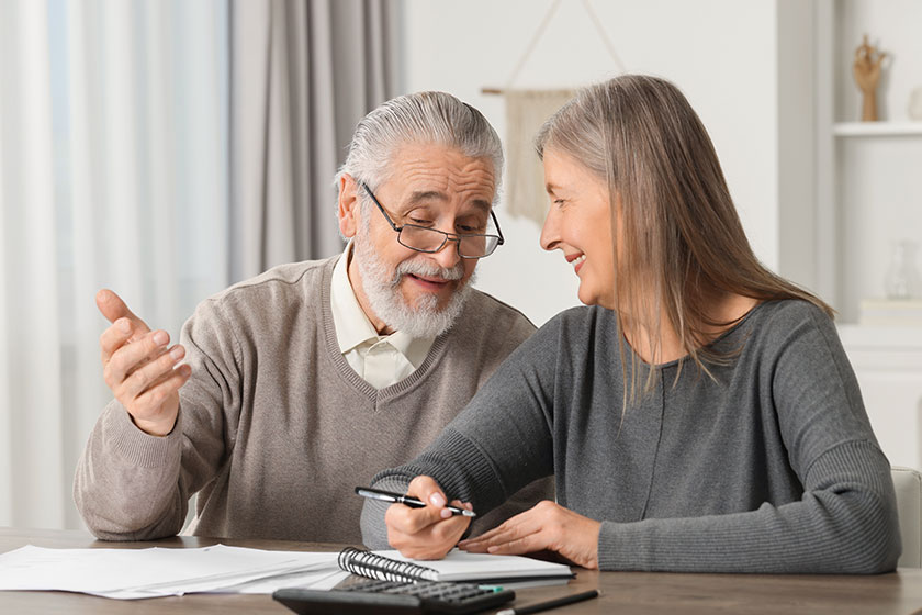 elderly couple papers discussing pension plan wooden table indoors