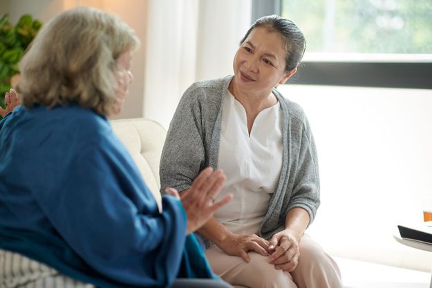 excited senior woman talking best friend while sitting sofa living
