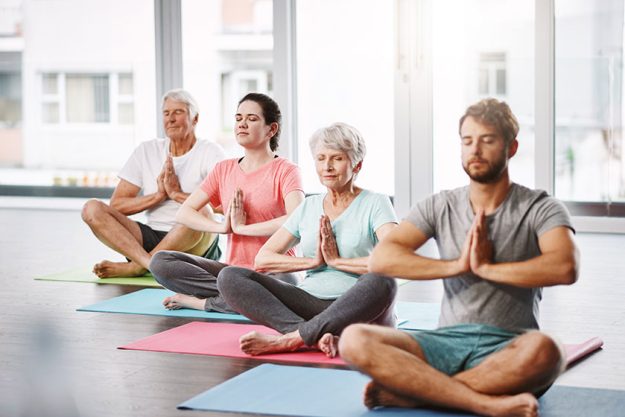 full length shot group people meditating while practicing yoga full length shot group people meditating while practicing yoga