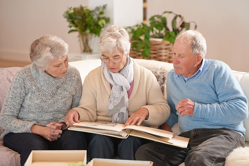 old people friends photo album memory talking retirement sofa together